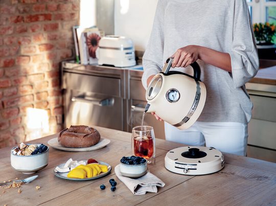 Žena připravuje snídani a zalévá čaj konvicí KitchenAid