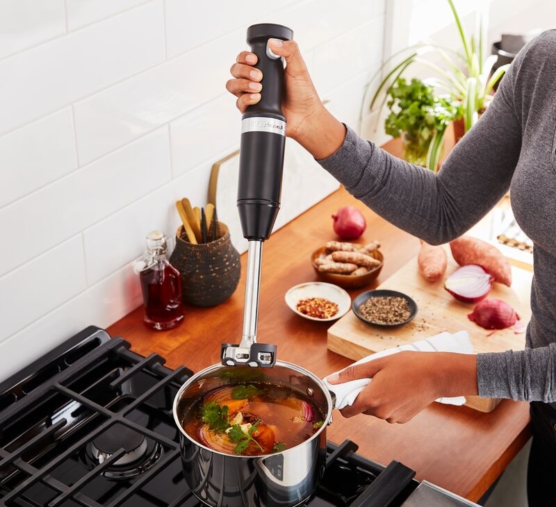 Žena mixuje polévku bezdrátovým tyčovým mixérem KitchenAid